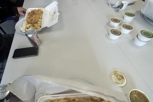 Fish and chips in takeaway boxes on a long table during the Head Office team lunch