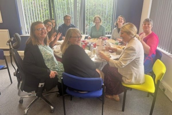 Head Office colleagues smiling around a table at the fish and chip lunch