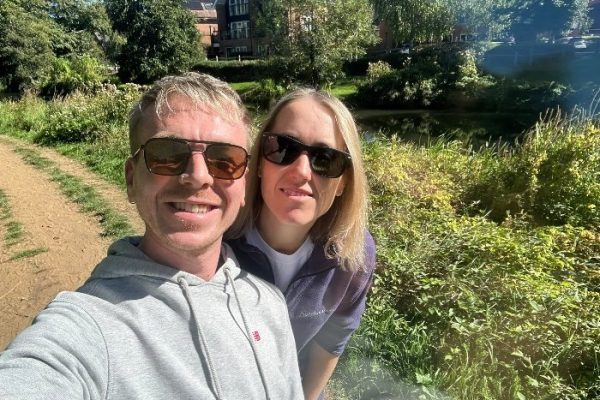 Two colleagues in sunglasses taking a selfie on a sunny riverside walk