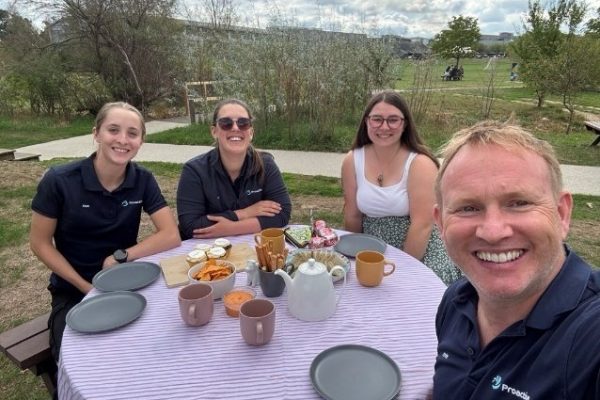 Four Proactive colleagues enjoying afternoon tea at an outdoor table in a park