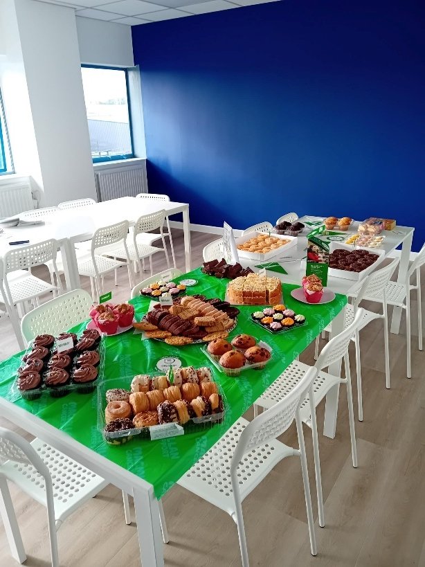 Tables covered in green Macmillan cloths and laid out with cakes, doughnuts and pastries for the coffee morning