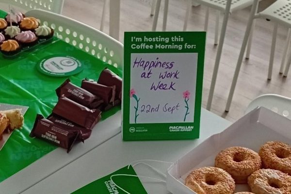 Doughnuts and chocolate bars beside a Macmillan sign reading Happiness at Work Week, 22nd Sept
