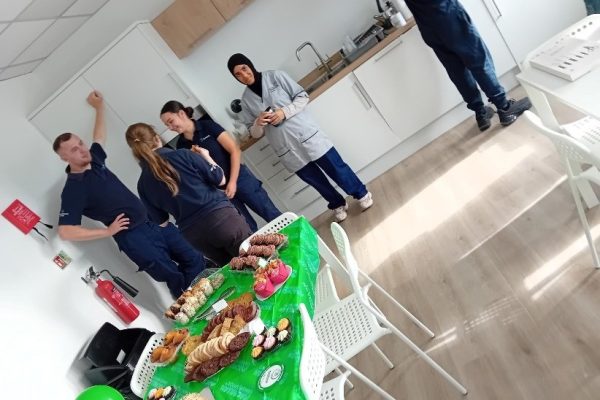 Colleagues chatting in the staff kitchen beside the coffee morning cake table