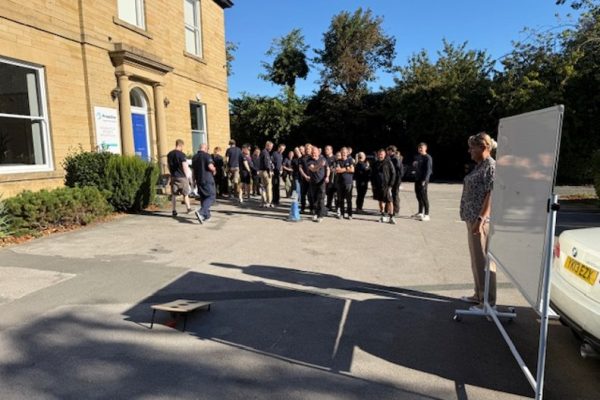 Crispin colleagues gathered in the car park for the Bean Bag Toss Challenge, with a scoreboard on a whiteboard